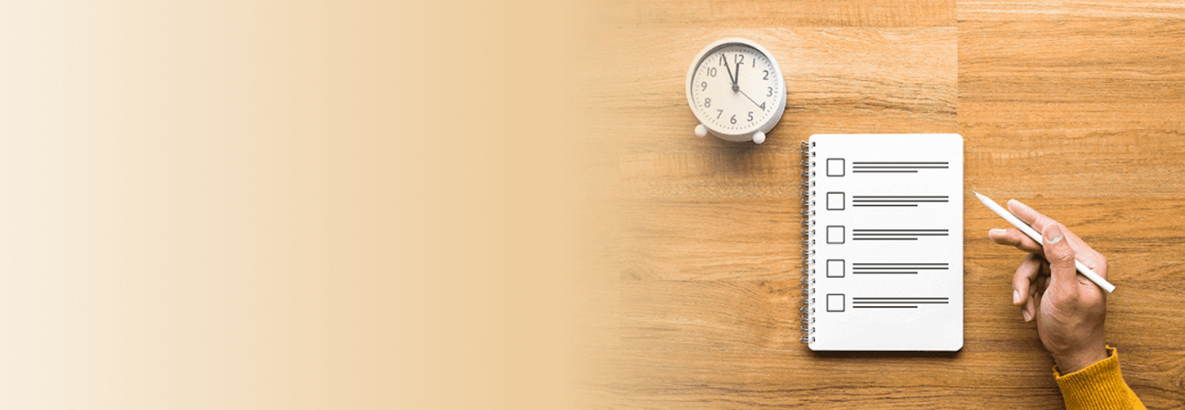 Notebook with checklist and alarm clock sitting on desk