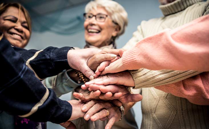 Group of women putting hands together to celebrate Breast Cancer Awareness month