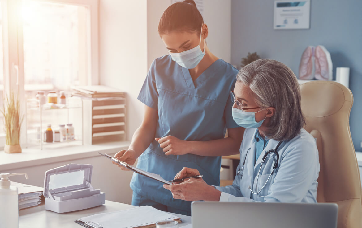 Doctor and nurse wearing face mask reviewing clipboard