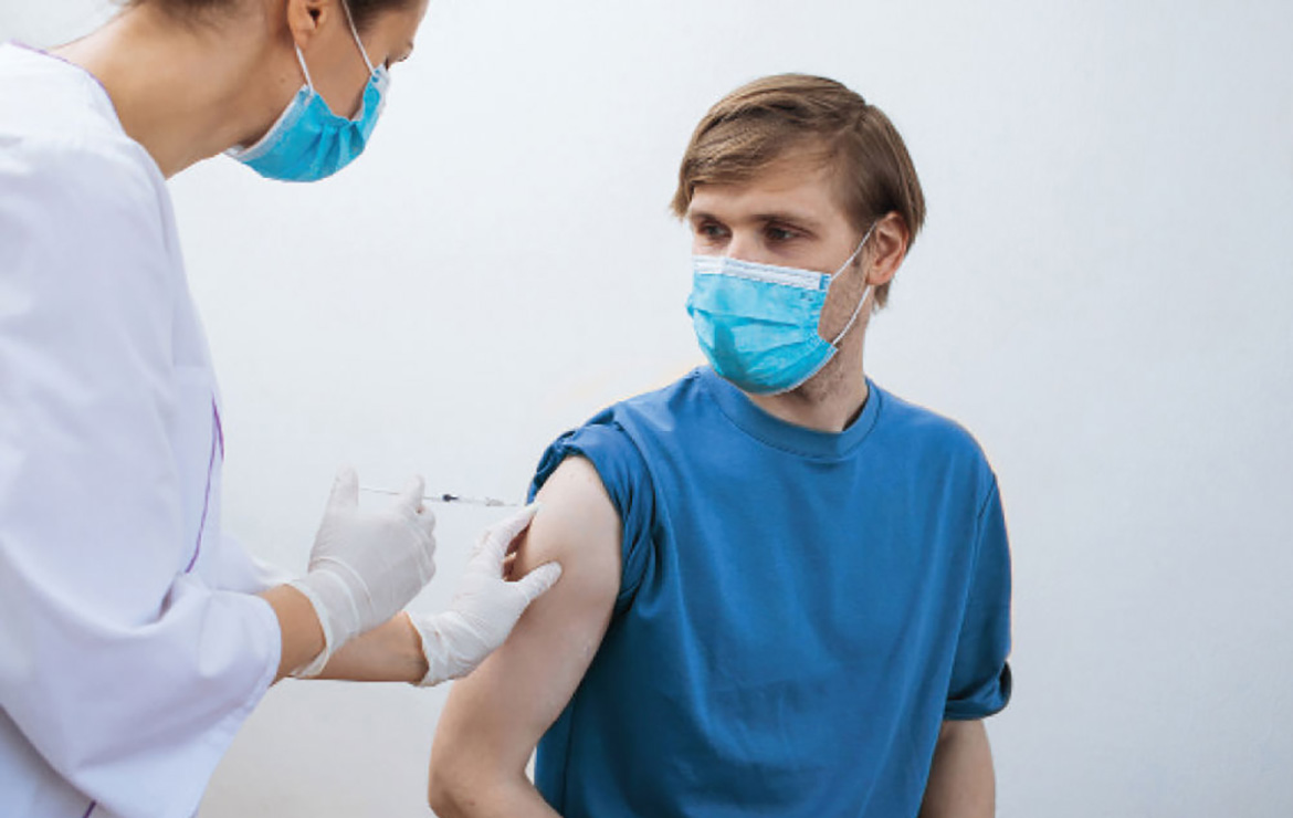 Masked patient getting vaccinated by masked nurse