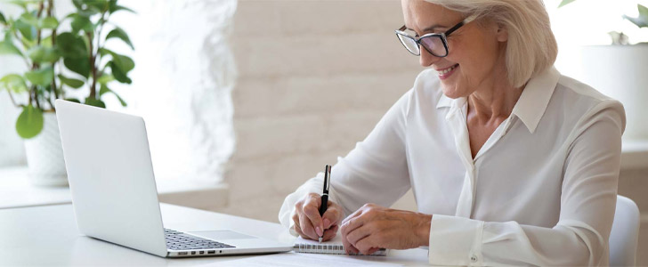 Older woman writing down notes on notepad