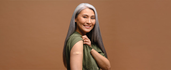 Older woman showing off flu shot bandage on arm