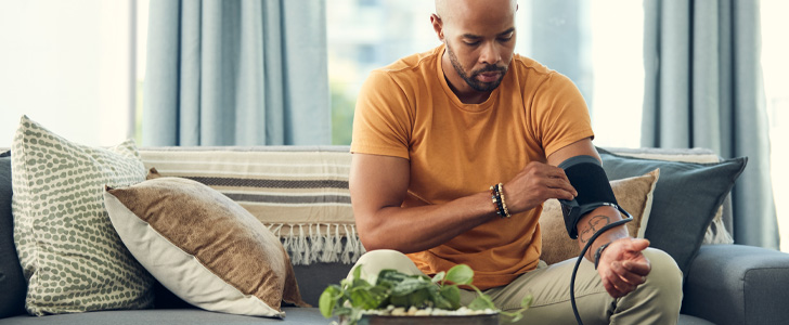 Man checking blood pressure while sitting in living room