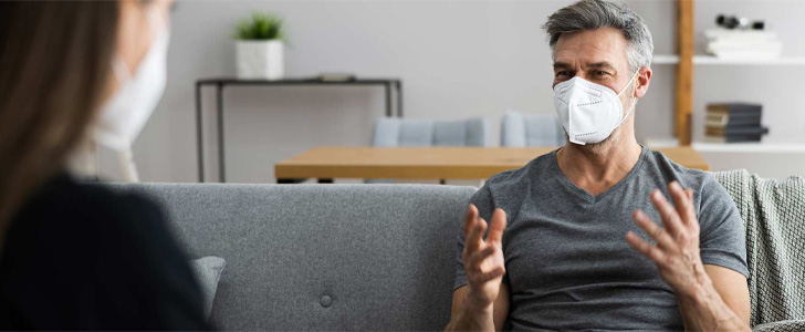 Patient wearing mask explaining to therapist