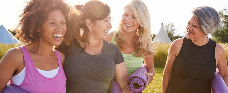 Group of women laughing while holding yoga mats