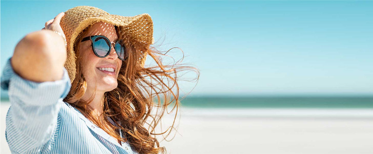 Woman wearing sunhat sitting on the beach