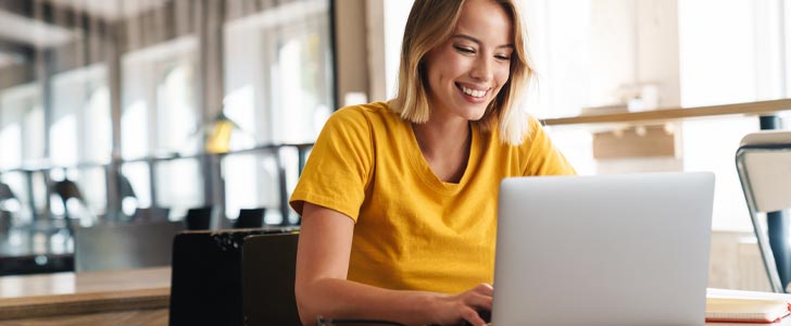 Woman smiling while typing on laptop