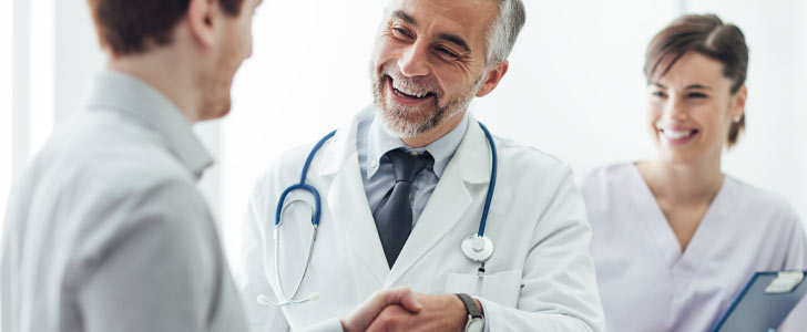 Doctor and assistant smiling together with patient