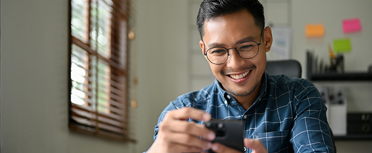 Smiling man wearing glasses using smartphone