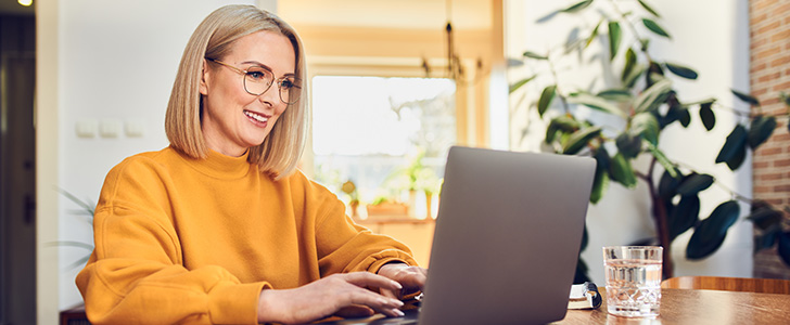 Smiling woman with glasses using laptop